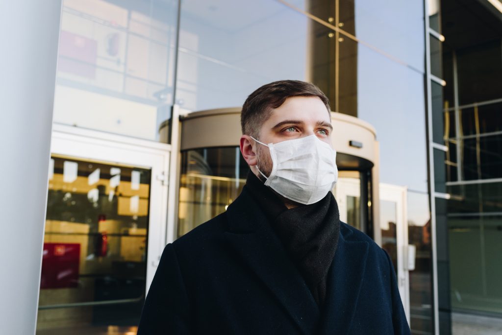 Man wearing face mask in front of a business building