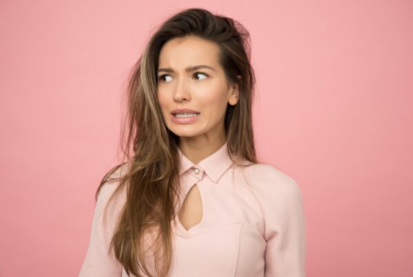 Woman wearing a pink top with an anxious facial expression