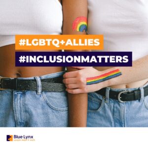 Two women next to each other with white tank tops and pride flag paint