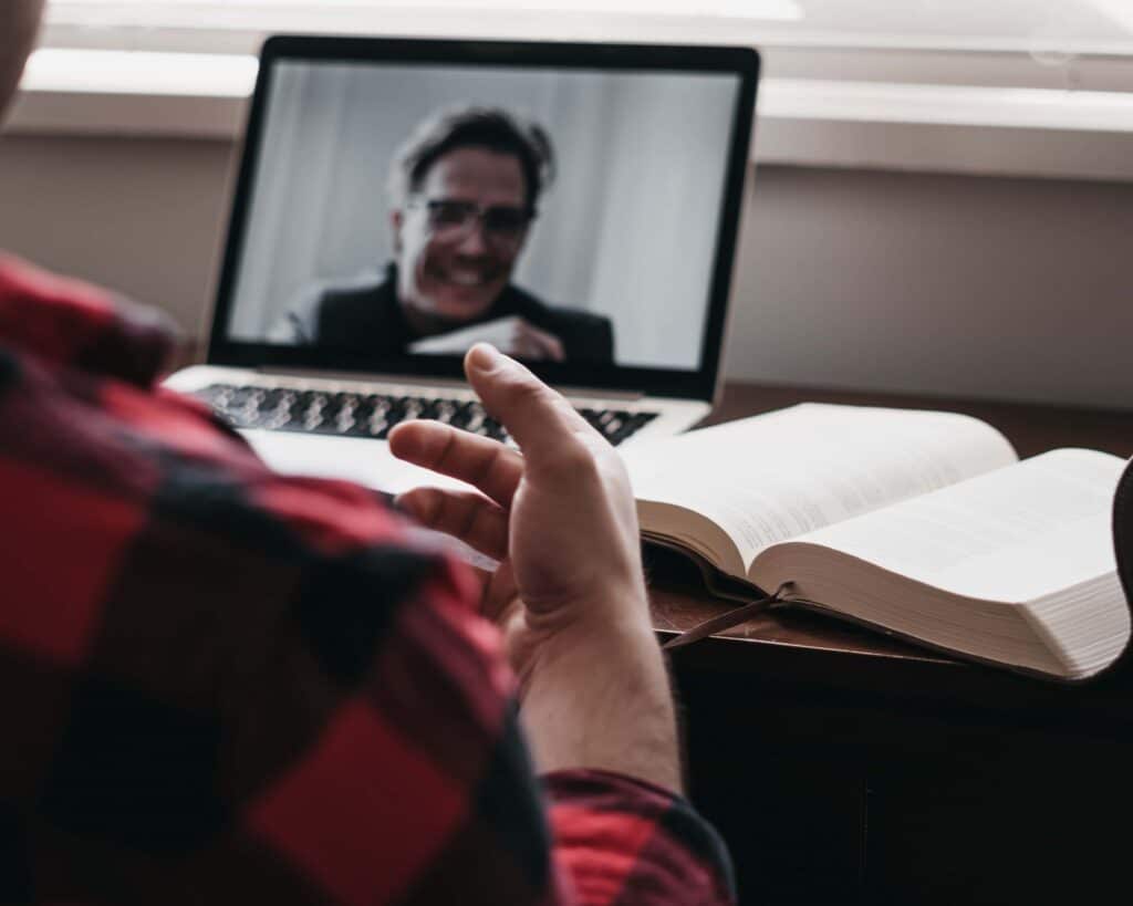 A person sitting at a desk with an open book, having an online call